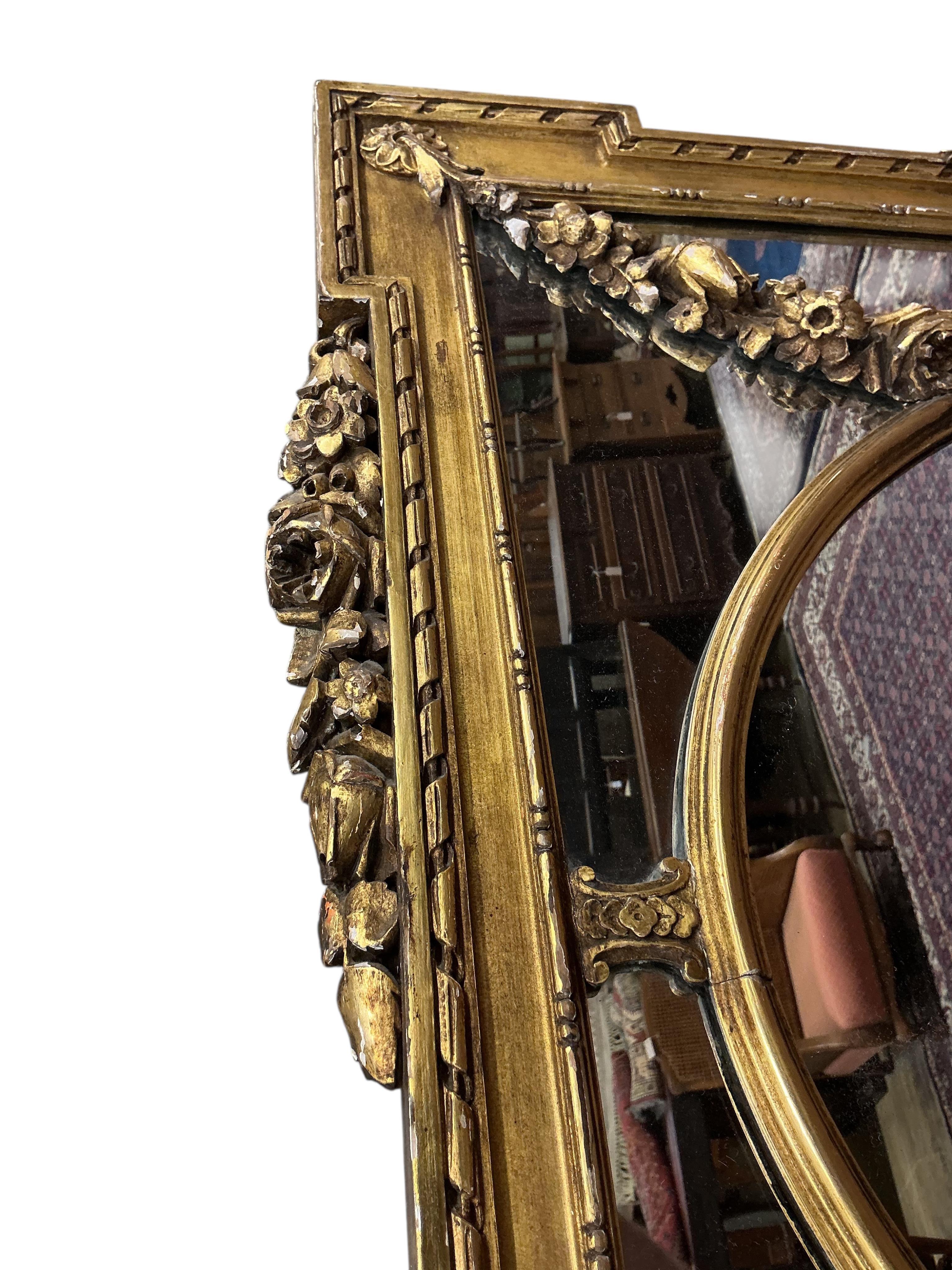 A Victorian style giltwood and composition overmantel mirror with cross torch and quiver crest, width 136cm, height 110cm